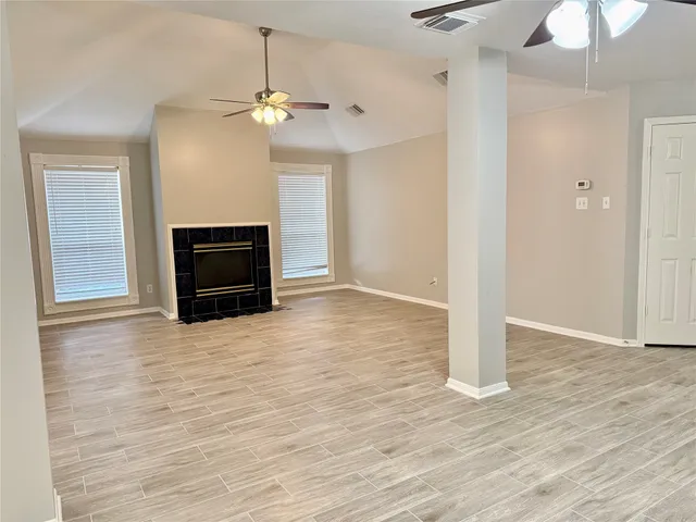 a view of an empty room with fire place and a window