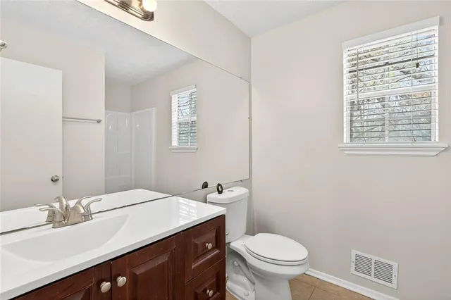 a bathroom with a granite countertop toilet a sink and a mirror