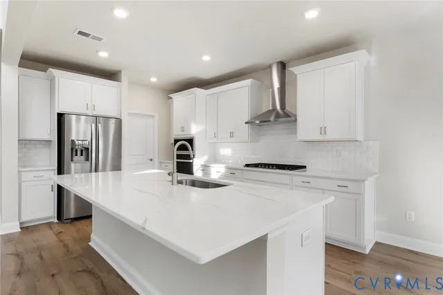 a kitchen with stainless steel appliances a sink a stove a refrigerator and cabinets