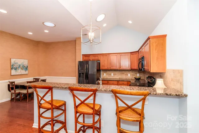 a kitchen with stainless steel appliances kitchen island granite countertop a table and chairs in it