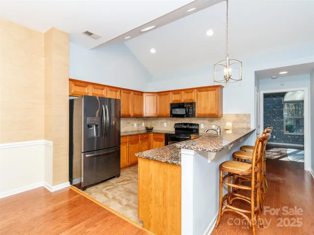 a kitchen with stainless steel appliances granite countertop a refrigerator a stove top oven a sink and dining table