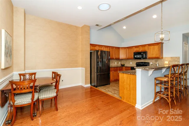 a kitchen with stainless steel appliances kitchen island granite countertop a table chairs microwave and sink