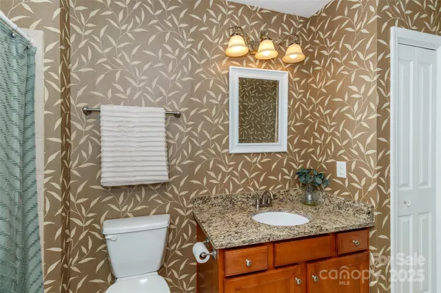 a bathroom with a granite countertop sink and a toilet