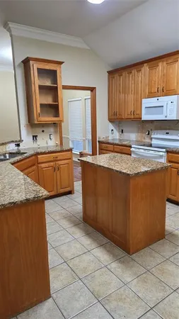 a large kitchen with granite countertop a sink a stove a counter space and cabinets