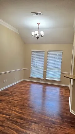 an empty room with wooden floor chandelier fan and windows