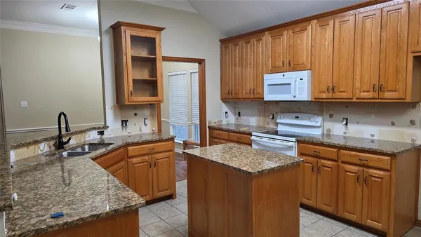 a kitchen with kitchen island granite countertop a sink stove and cabinets