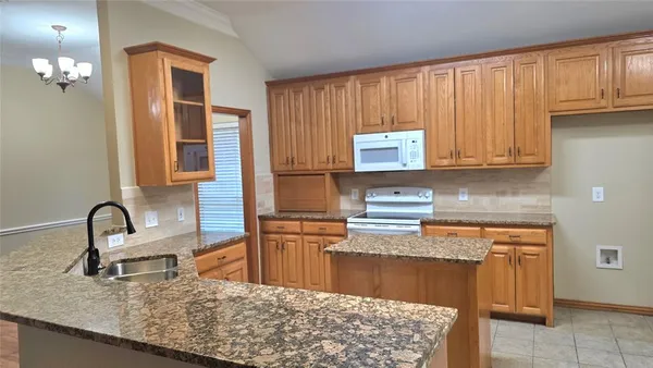 a kitchen with kitchen island granite countertop a sink stove and cabinets