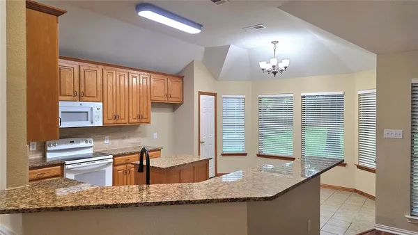 a kitchen with kitchen island granite countertop a sink a counter top space and cabinets