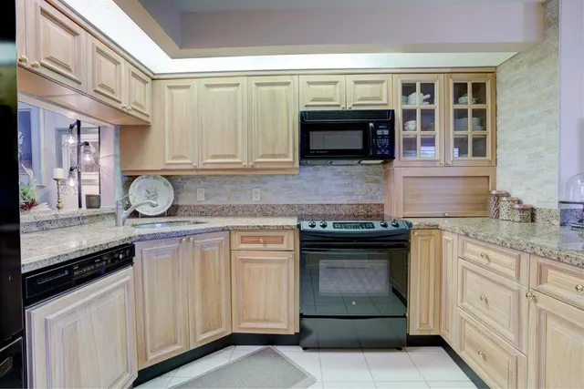 a kitchen with granite countertop a stove top oven microwave and cabinets