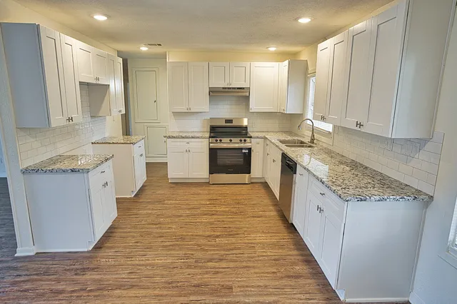 a large kitchen with granite countertop a sink and cabinets