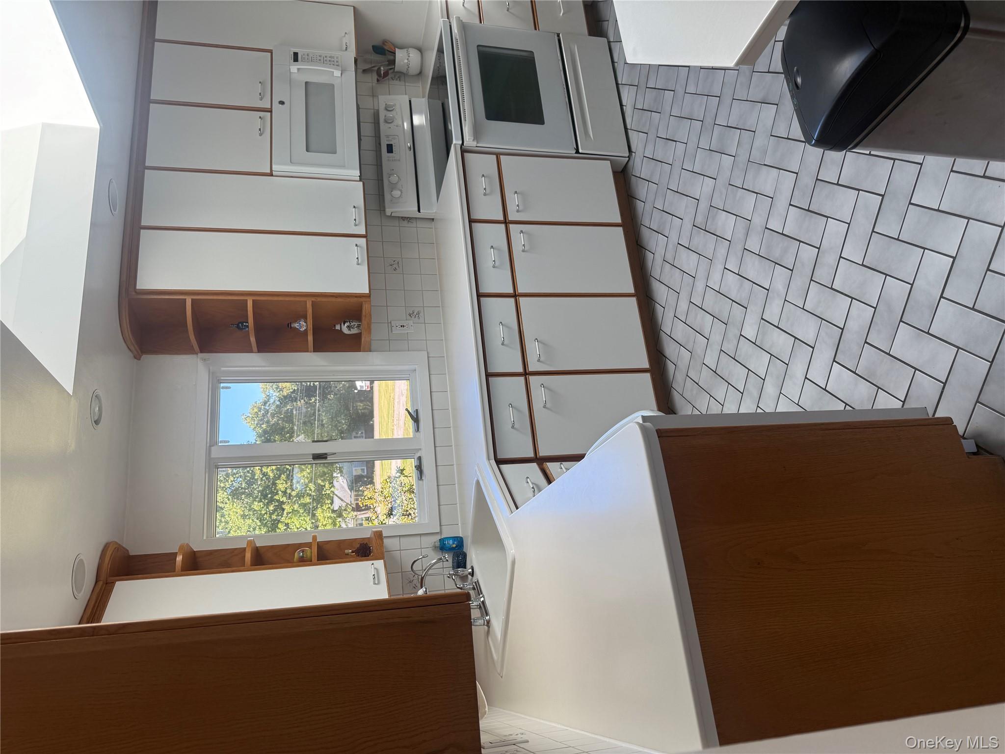 18 Adams Road Ossining, NY 10562 - Photo 9 of 41 Kitchen with stove, light countertops, white cabinetry, and tasteful backsplash