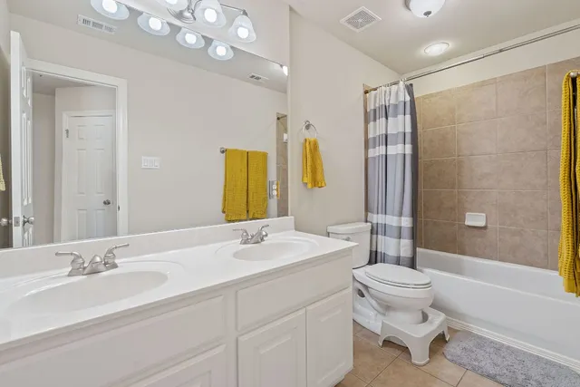 a bathroom with a double vanity sink toilet mirror and shower