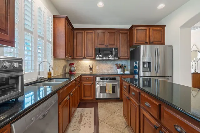 a kitchen with stainless steel appliances granite countertop a refrigerator stove top oven a sink and dishwasher