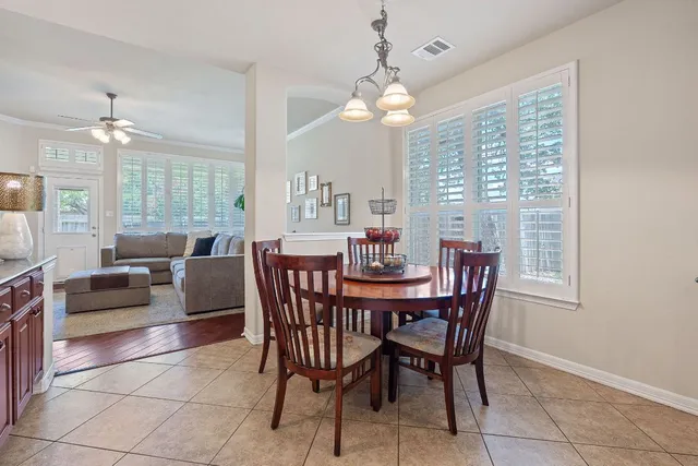 a view of a dining room with furniture a chandelier and large windows