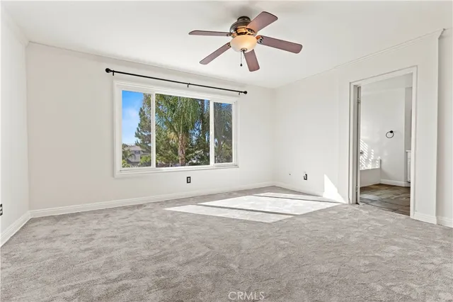 a view of empty room with window and ceiling fan