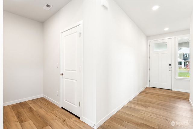 a kitchen with granite countertop a refrigerator oven a sink dishwasher and white cabinets with wooden floor