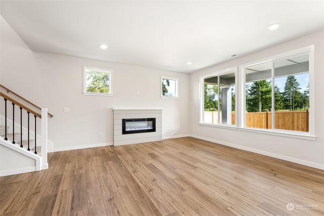 a view of an empty room with wooden floor and a fireplace