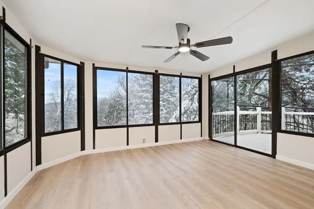a view of an empty room with wooden floor and a window