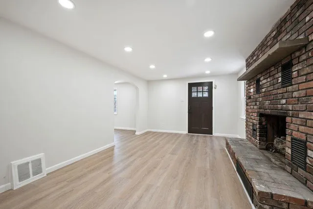a view of empty room with wooden floor and fireplace