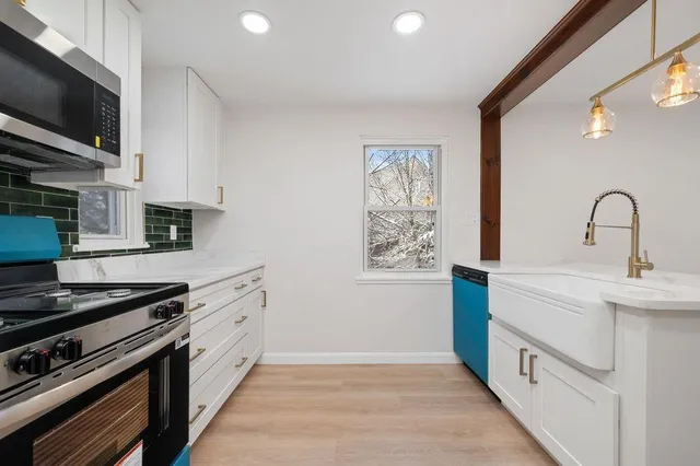 a kitchen with stainless steel appliances a sink dishwasher a stove and a microwave oven with cabinets