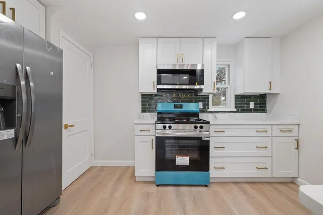 a kitchen with stainless steel appliances white cabinets a stove a refrigerator and a microwave