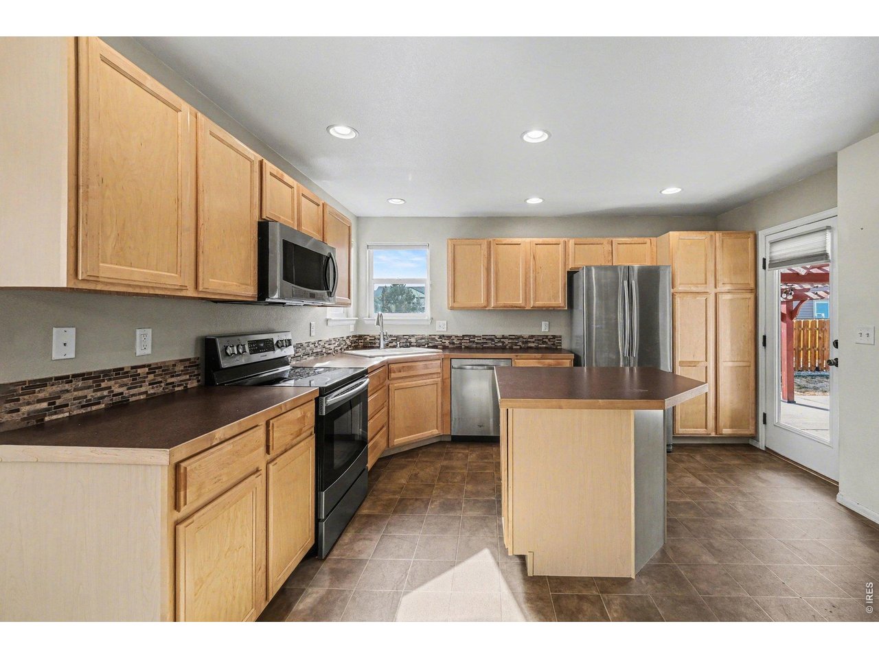 7347 Atlantis Street Wellington, CO 80549 - Photo 2 of 23 Kitchen has a spacious island and beautiful tile backsplash