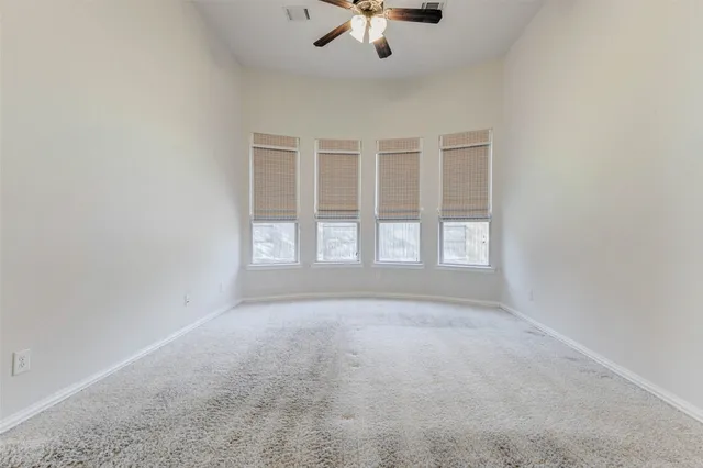 an empty room with windows and chandelier fan