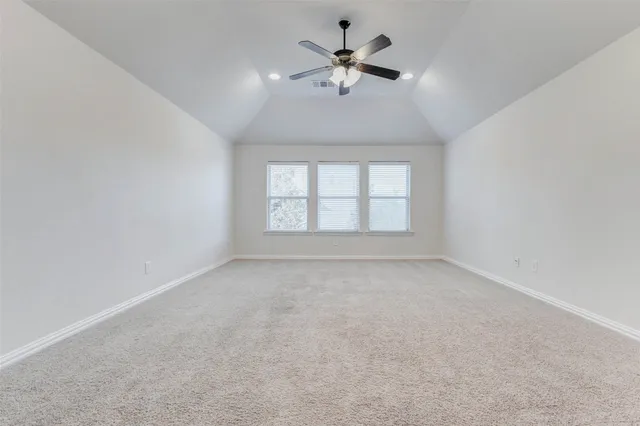 an empty room with a chandelier fan and windows