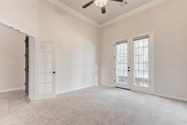 an empty room with chandelier fan and windows