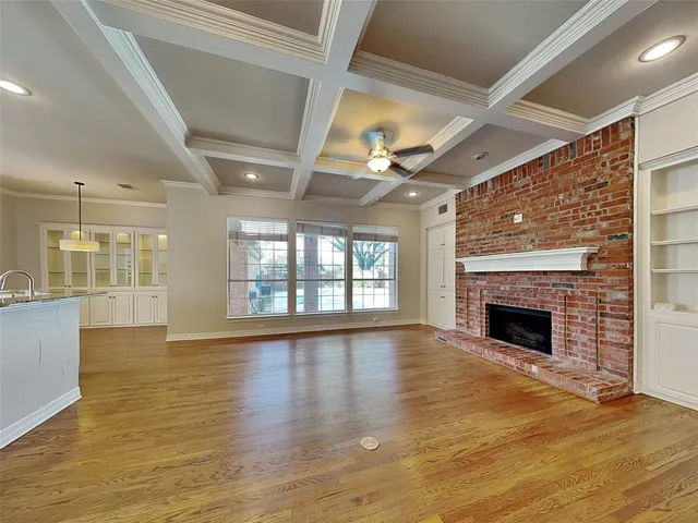 an empty room with wooden floor fireplace and windows