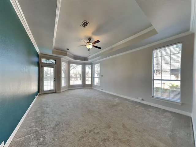 an empty room with chandelier fan and windows