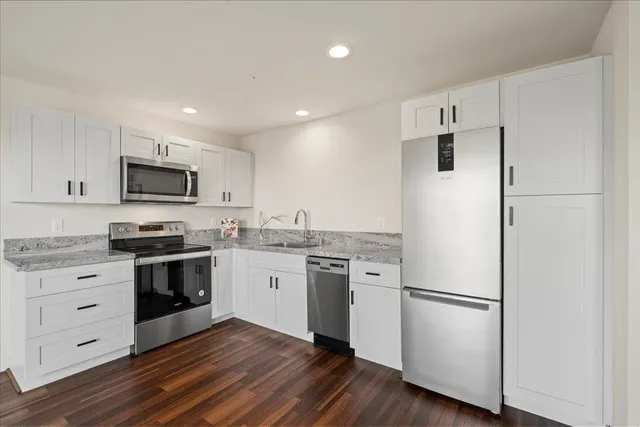 a kitchen with stainless steel appliances granite countertop a stove a sink and a microwave