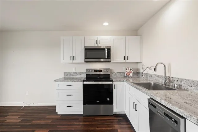 a kitchen with stainless steel appliances a sink cabinets and wooden floor