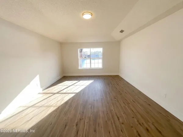 an empty room with wooden floor and windows