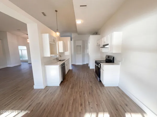 a large kitchen with cabinets wooden floor and stainless steel appliances