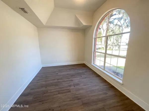 an empty room with wooden floor windows and outdoor view
