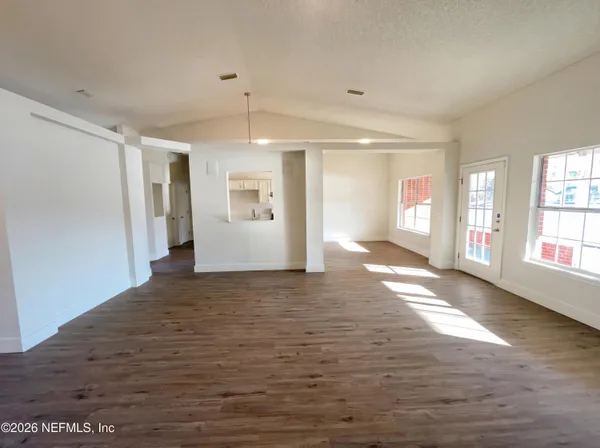 a view of an empty room with window and wooden floor