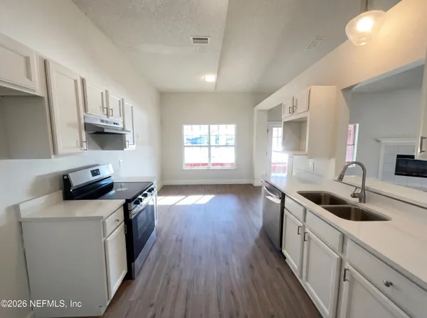 a kitchen with granite countertop a sink wooden floor and stainless steel appliances