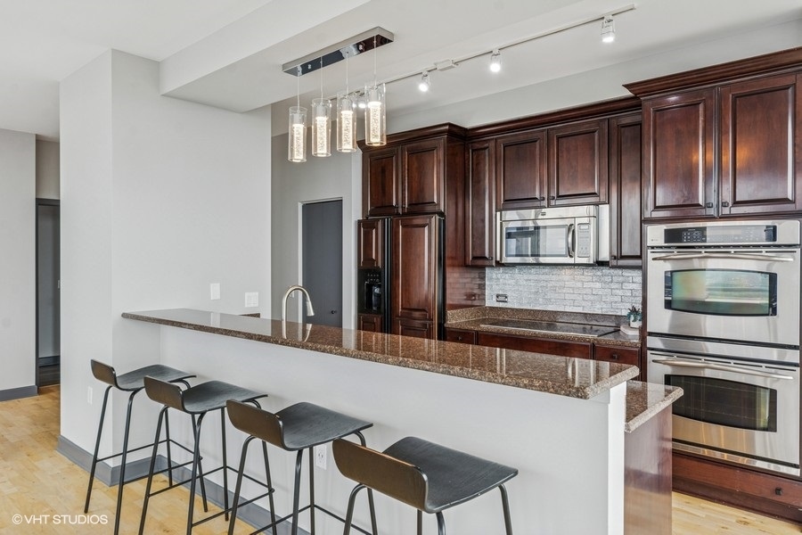 1235 South Prairie Avenue, Unit 3605 Chicago, IL 60605 - Photo 11 of 34 a kitchen with kitchen island granite countertop wooden cabinets and stainless steel appliances