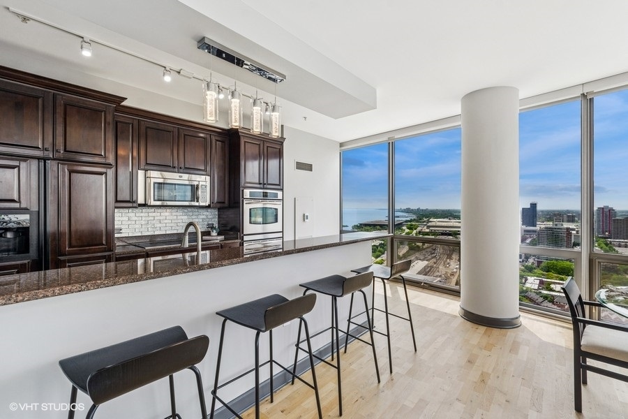 1235 South Prairie Avenue, Unit 3605 Chicago, IL 60605 - Photo 8 of 34 a kitchen with stainless steel appliances kitchen island granite countertop a table chairs in it and wooden floors