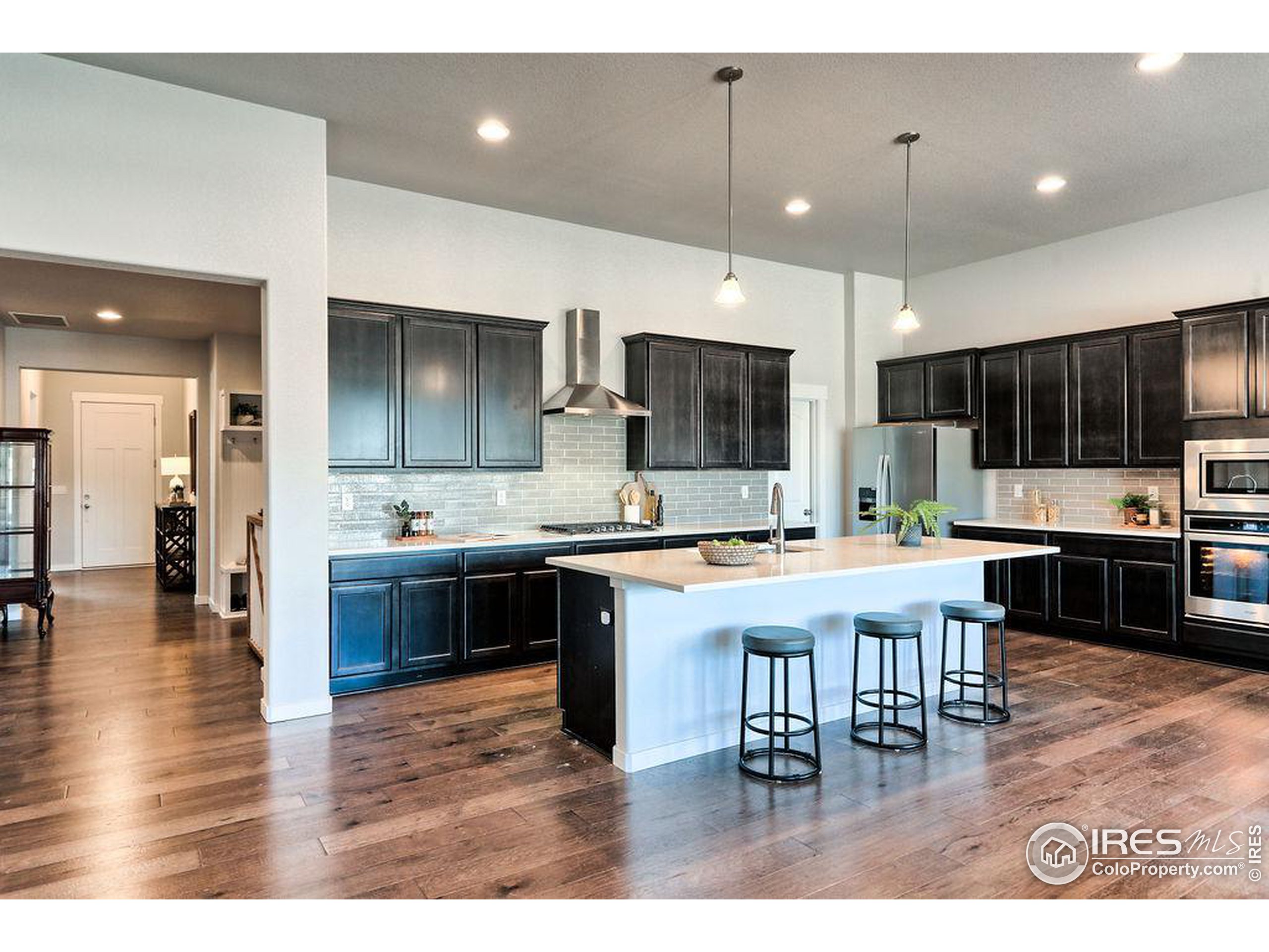 a kitchen with stainless steel appliances kitchen island granite countertop a table chairs sink and cabinets