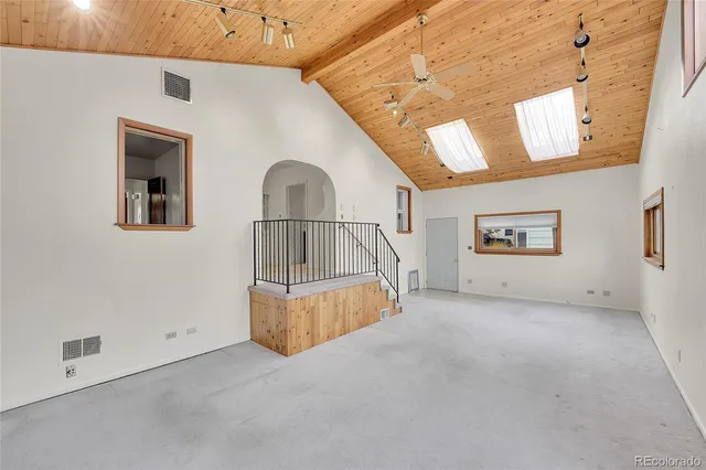 an empty room with windows and ceiling fan