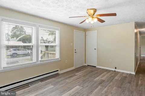 a view of an empty room with window and wooden floor