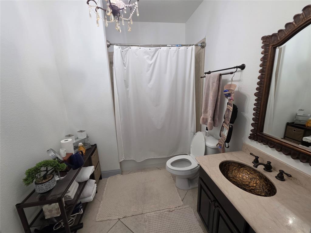809 Rockingham Drive Irving, TX 75063 - Photo 10 of 30 Ornate chandelier, decorative wall mirror, stone-finish countertop, hammered metal vessel sink, and a dark wood-finish vanity