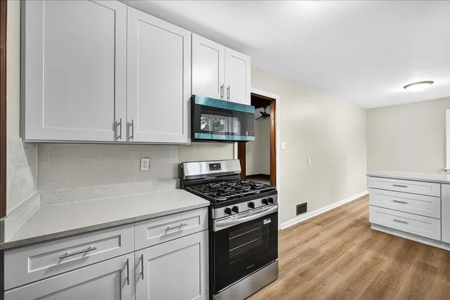 a kitchen with granite countertop white cabinets and stainless steel appliances