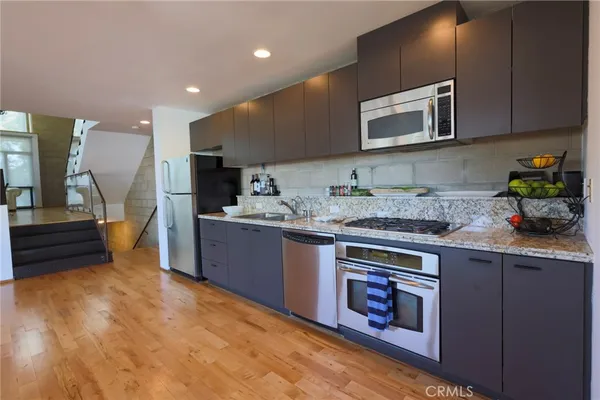 a kitchen with stainless steel appliances granite countertop a stove a sink and a microwave