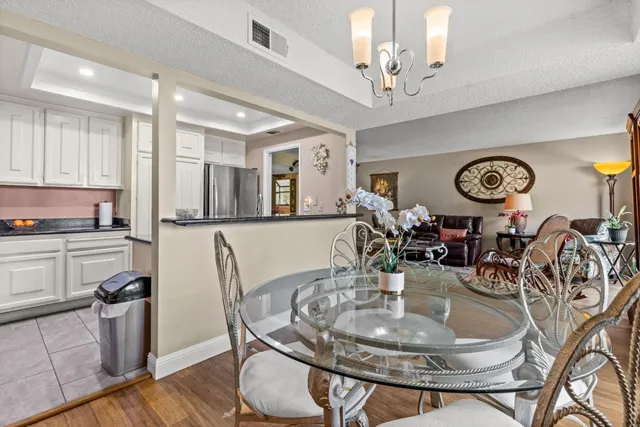 a dining room with wooden floor a chandelier a wooden table and chairs