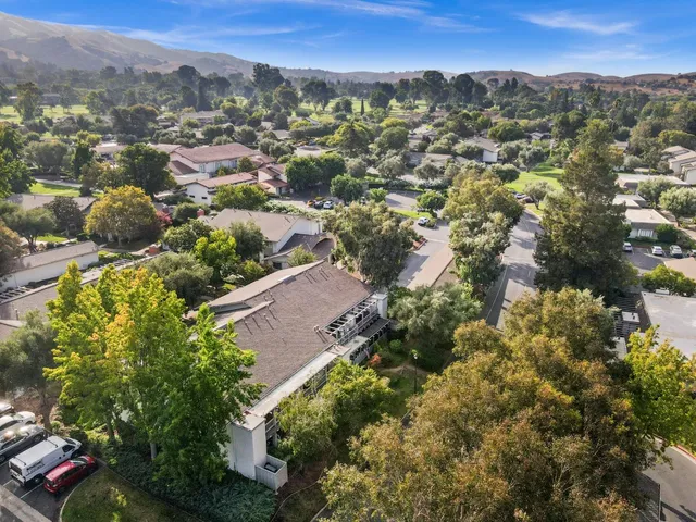 an aerial view of residential houses with outdoor space and trees