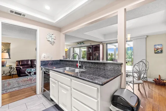 a kitchen with stainless steel appliances granite countertop a sink a counter space and living room view