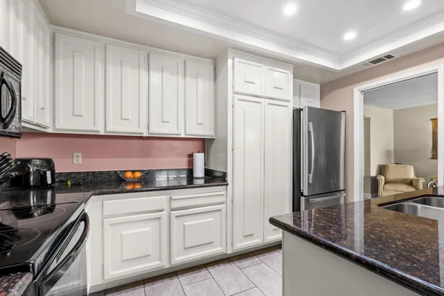 a kitchen with granite countertop a refrigerator sink and cabinets
